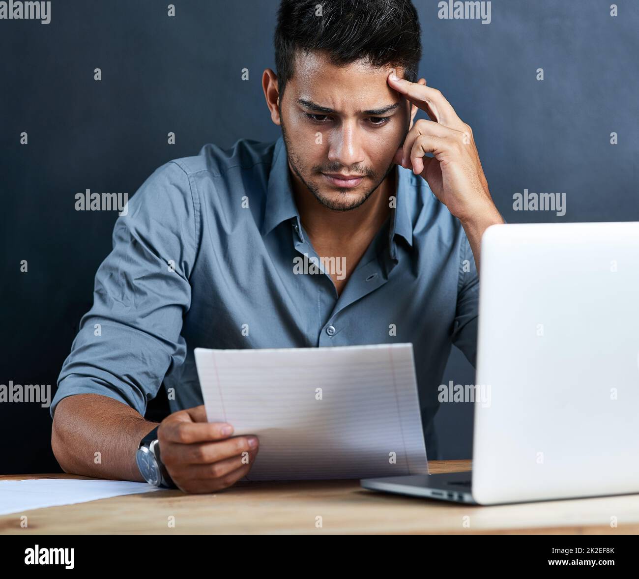 Some challenges are more of a struggle than others. Cropped shot of a handsome young businessman looking stressed out while working at his desk. Stock Photo