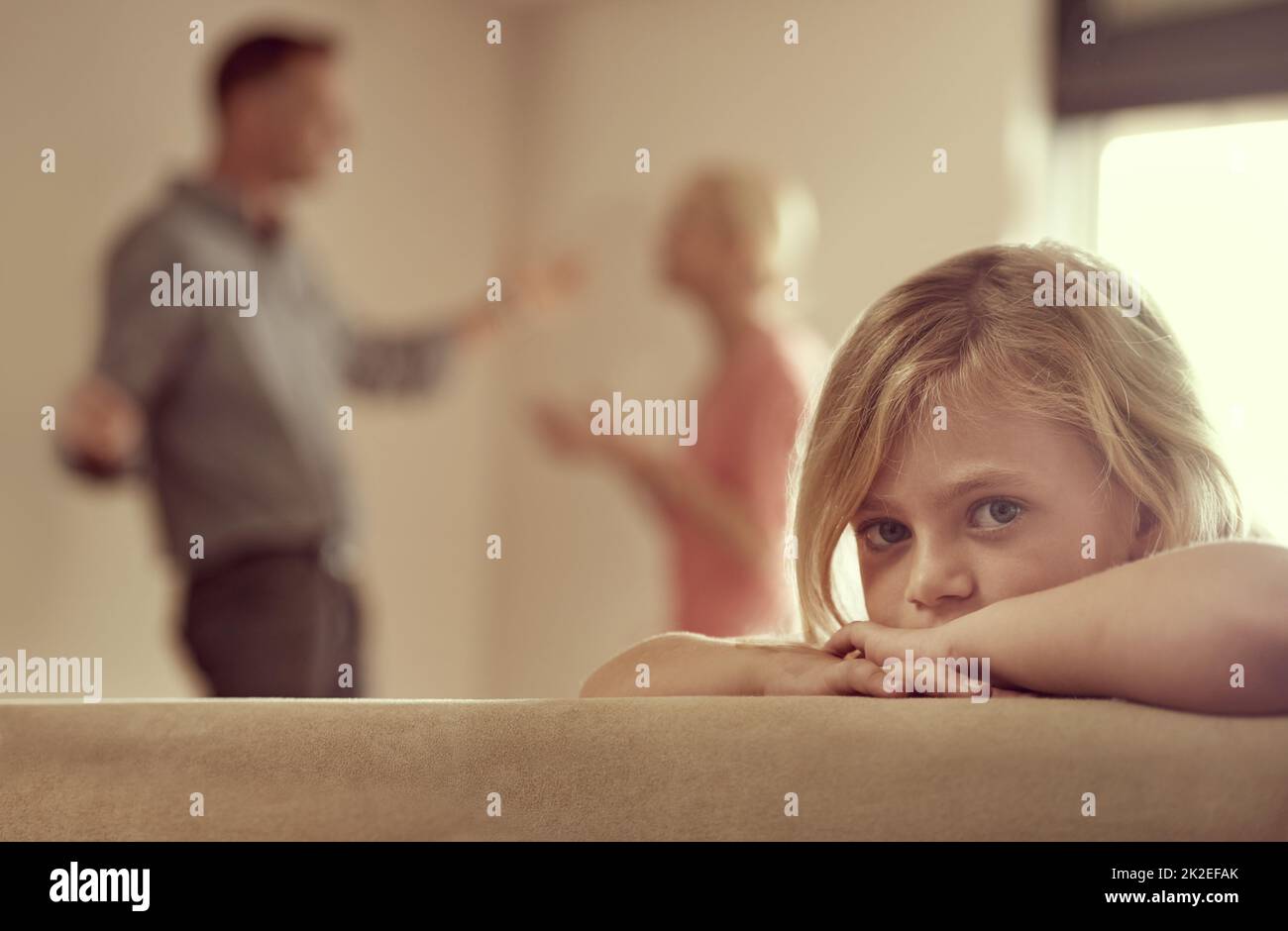 Why do they have to fight. Shot of a little girl looking unhappy as her parents argue in the background. Stock Photo
