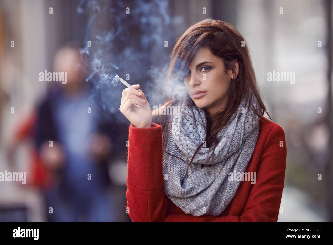 Ill bring the smoke, you bring the fire. Portrait of a beautiful and fashionable young woman smoking a cigarette in an urban setting. Stock Photo