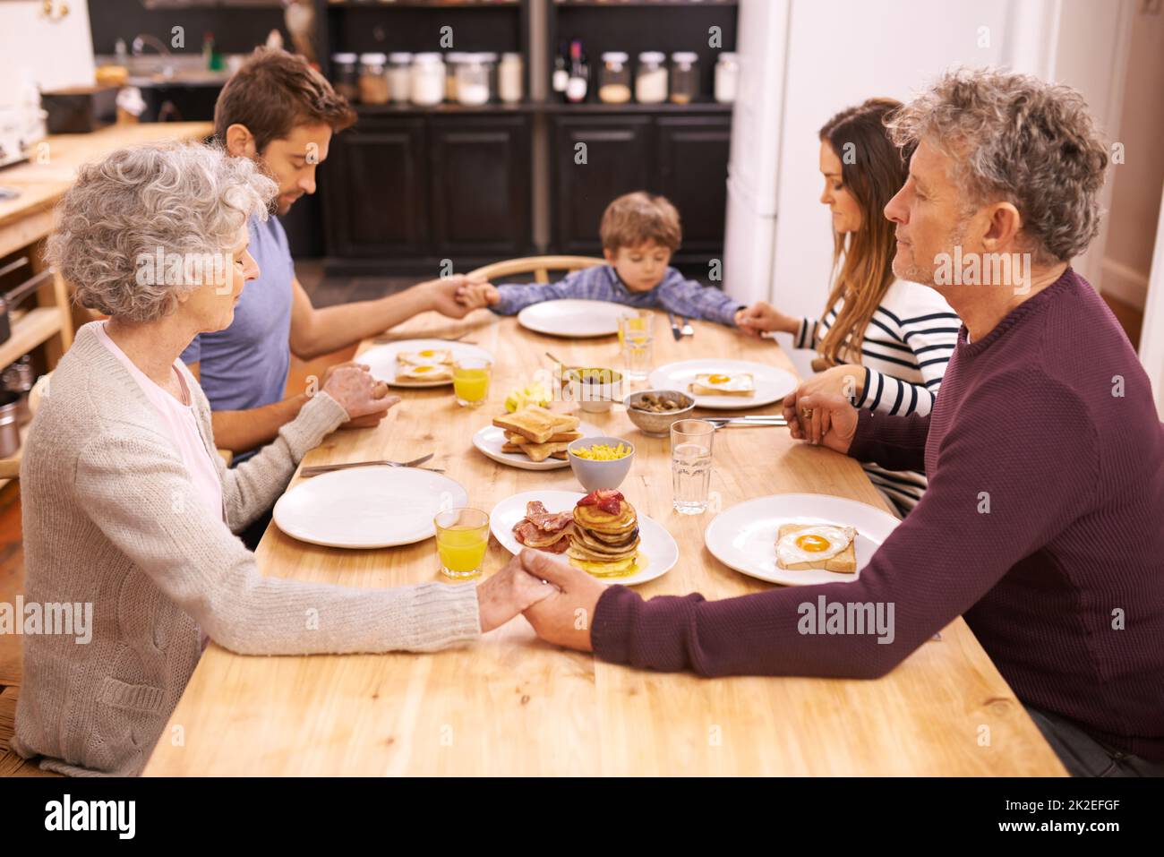 Bless this food to our bodies. Cropped shot of a family saying grace before eating breakfast. Stock Photo
