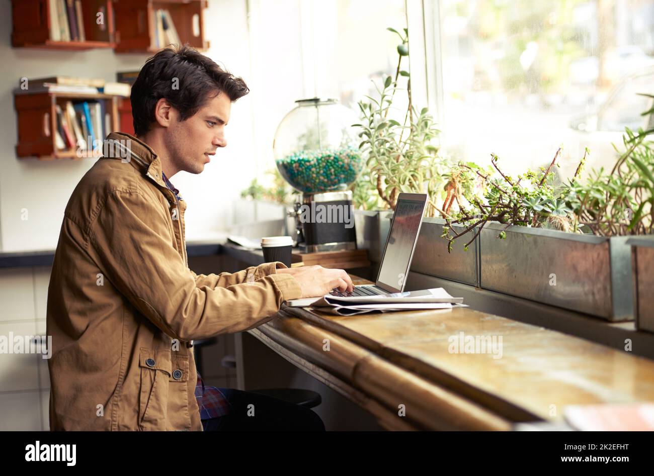 But first, coffee. Cropped shot of a young man using a laptop in a cafe. Stock Photo