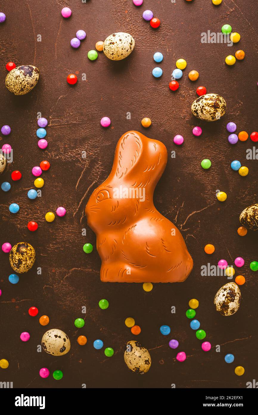 Delicious chocolate easter eggs, bunny and sweets on dark brown background Stock Photo