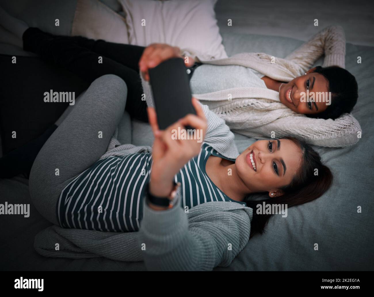 Were always selfie ready. Shot of two young women lying taking selfies while lying on a bed. Stock Photo