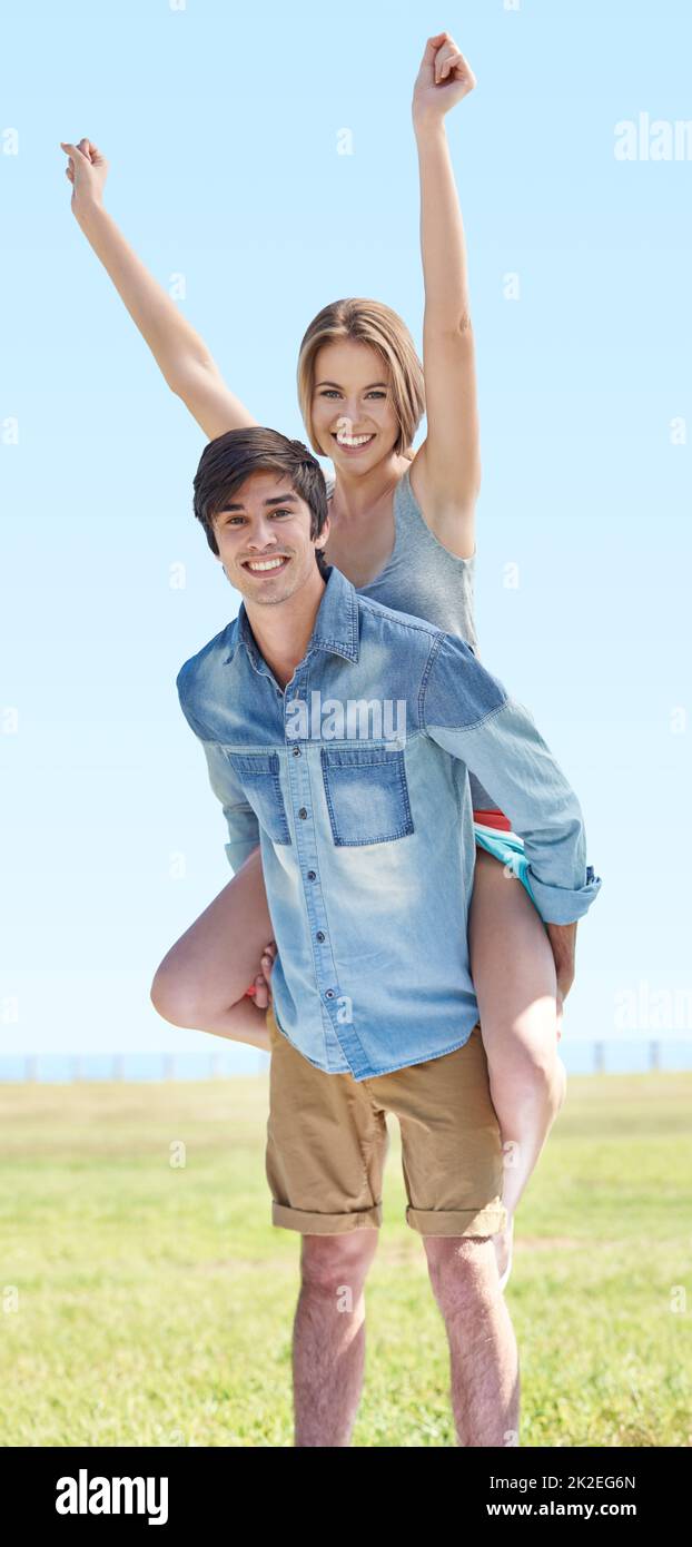 Ahhhhh, young love. A young man piggybacking his girlfriend in the outdoors. Stock Photo