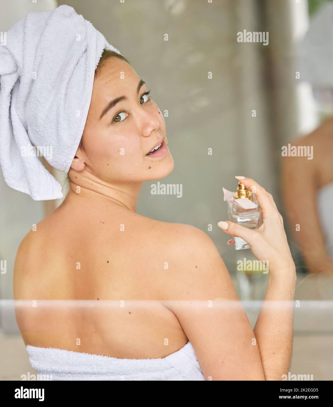 Self care makes me feel amazing. Shot of a young woman spraying perfume during her morning beauty routine. Stock Photo