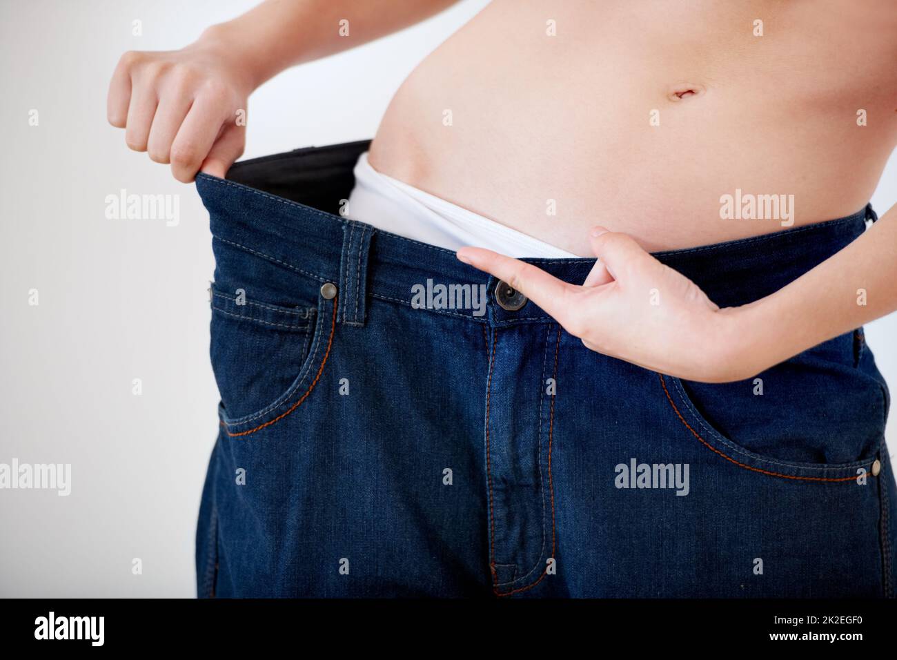 2 sizes smaller. Cropped image of a woman pulling the waistband of her