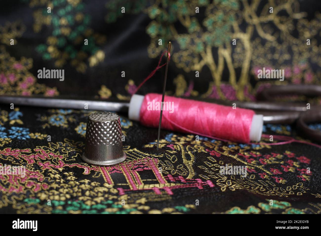 Pink Thread and Thimble on Vintage Chinese Black Silk Stock Photo