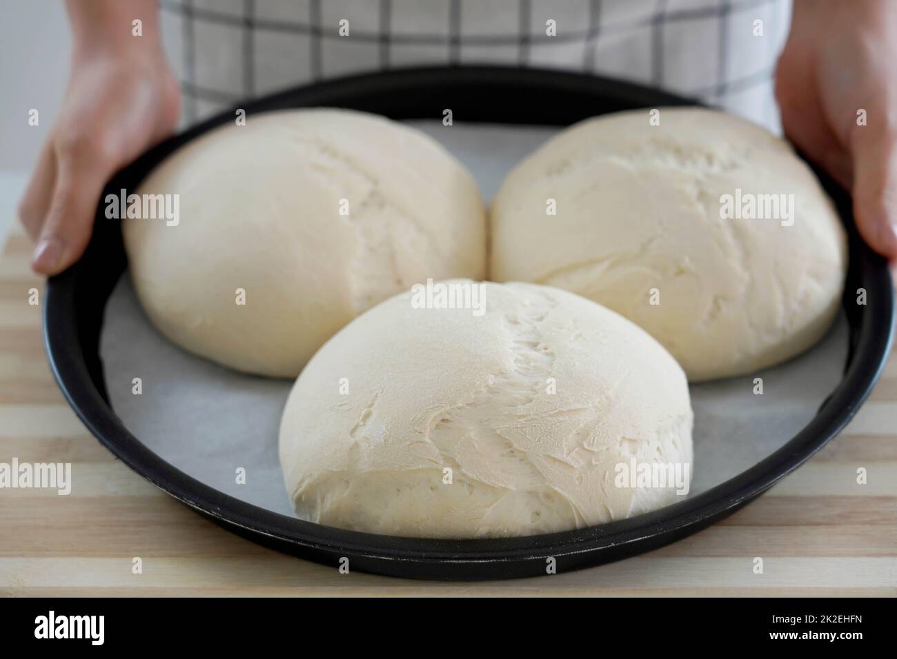 Woman showing three homemade loaves of bread in baking tray ready to be baked Stock Photo