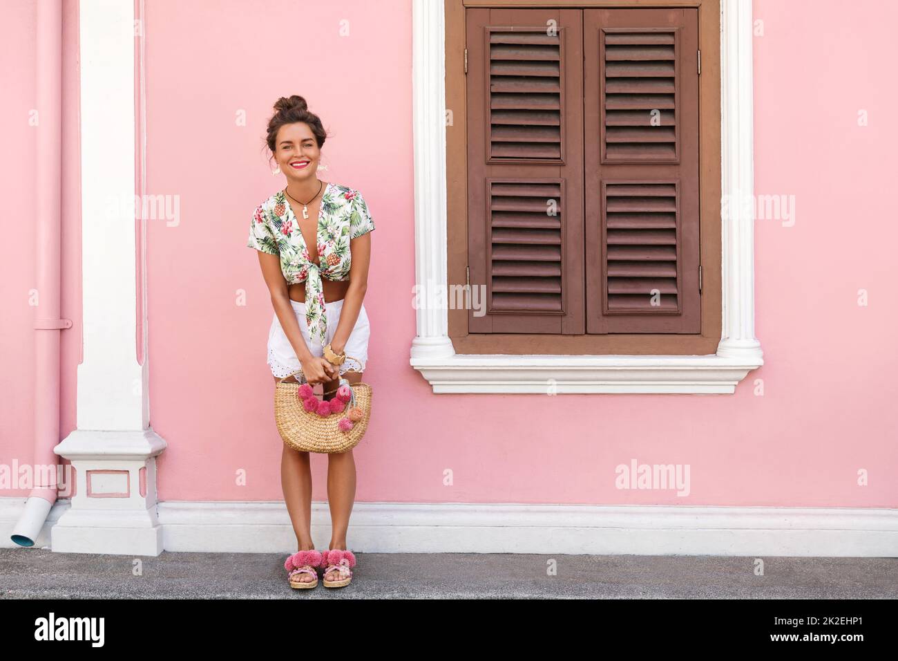 Beautiful and stylish woman posing beside the house with a pink wall Stock Photo