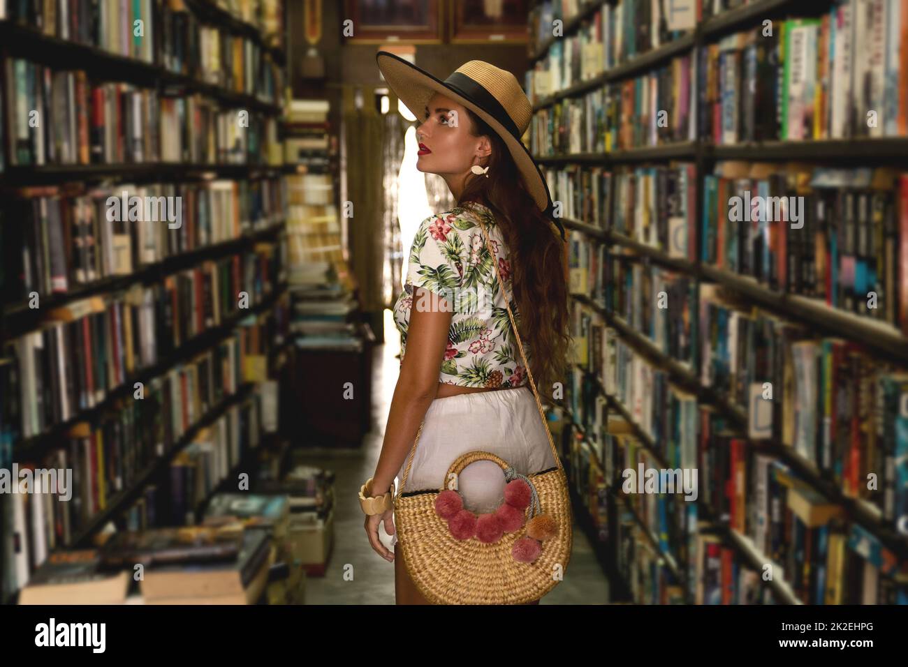 Beautiful girl wearing stylish outfit looking for interesting book in the vintage bookstore Stock Photo