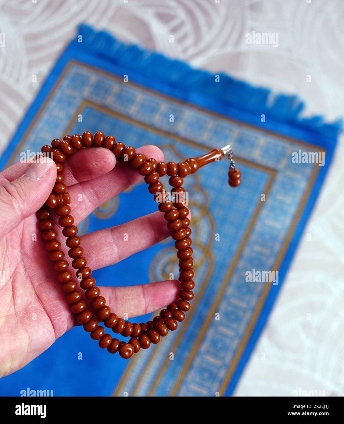 A prayer rosary and prayer rug in a Muslim's hand, closeup of rosary