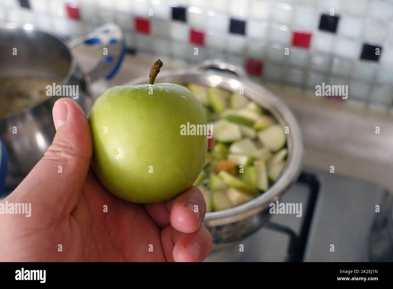 freshly chopped green sour apple pieces boiling in pot,make homemade apple juice Stock Photo