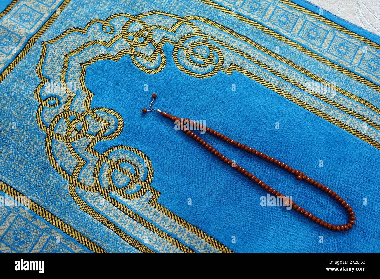 A prayer rosary and prayer rug in a Muslim's hand, closeup of rosary
