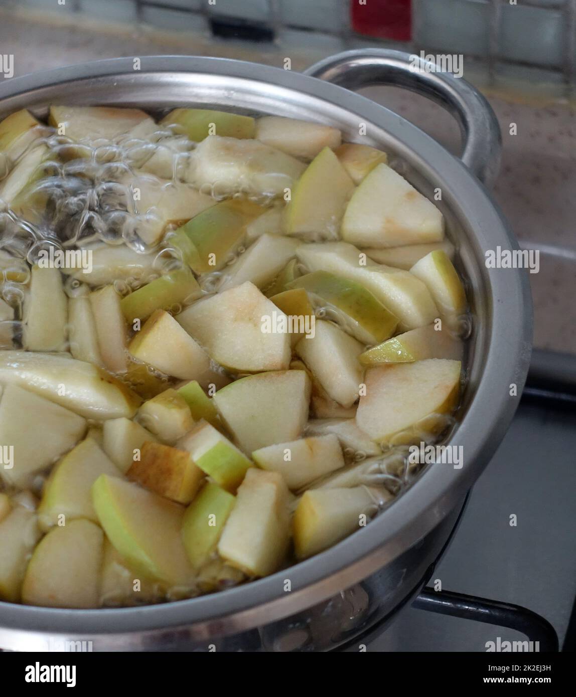 freshly chopped green sour apple pieces boiling in pot,make homemade apple juice Stock Photo