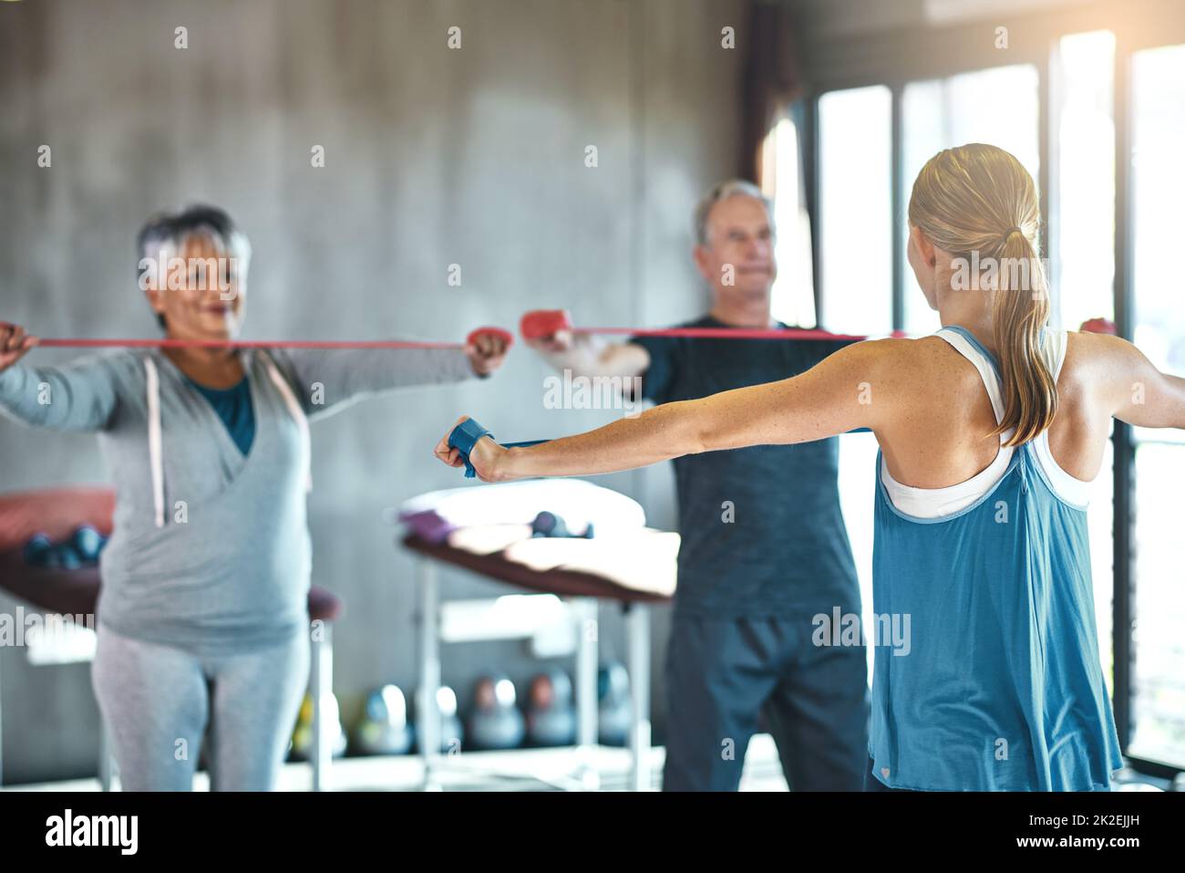 The senior years dont have to be the sedentary years. Shot of a senior man and woman using resistance bands with the help of a physical therapist. Stock Photo