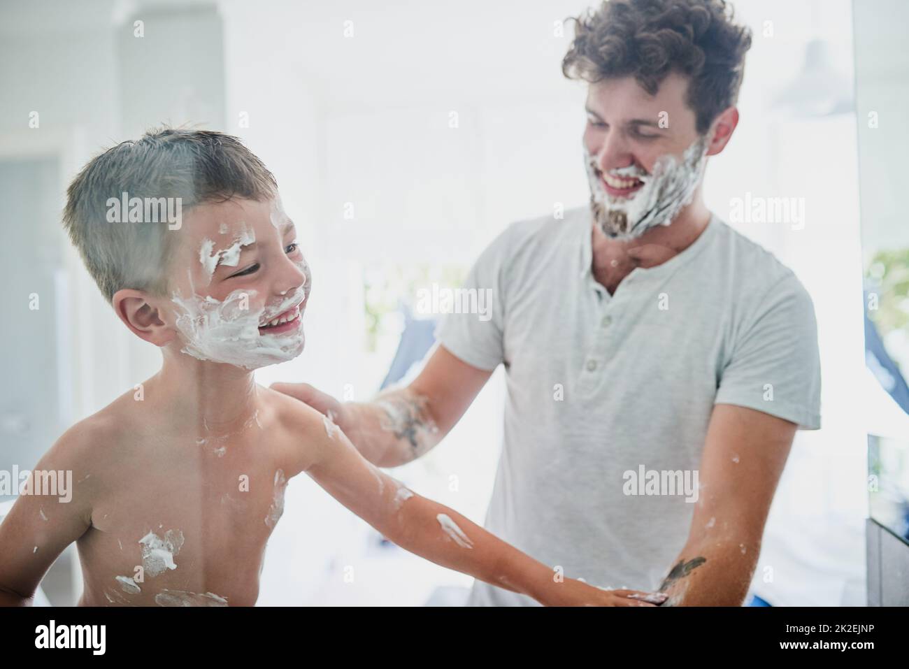 When it gets messy, it gets fun. Shot of a father teaching his little son how to shave in the bathroom at home. Stock Photo