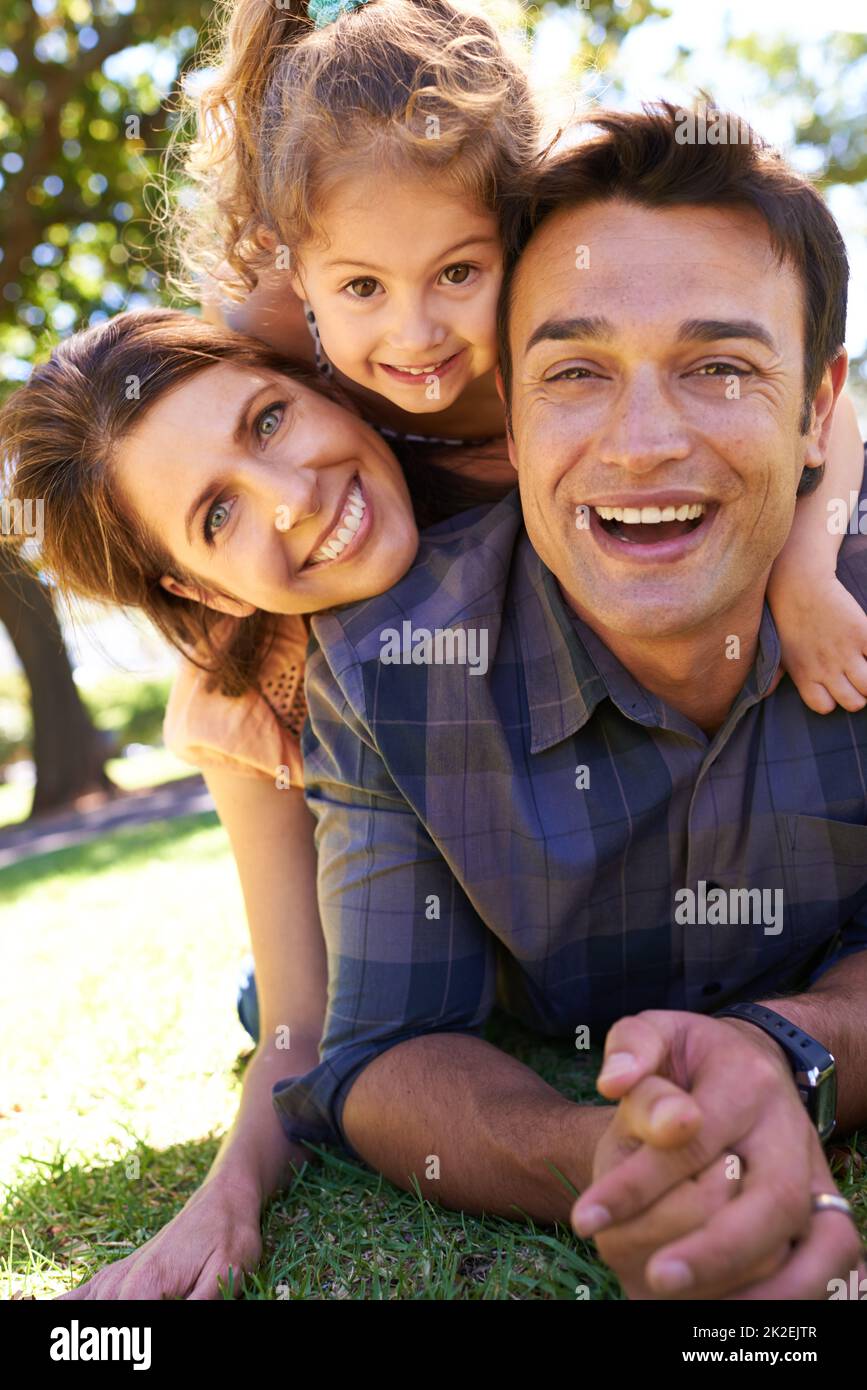The happiest of families. Shot of a young family lying on the grass in the park. Stock Photo