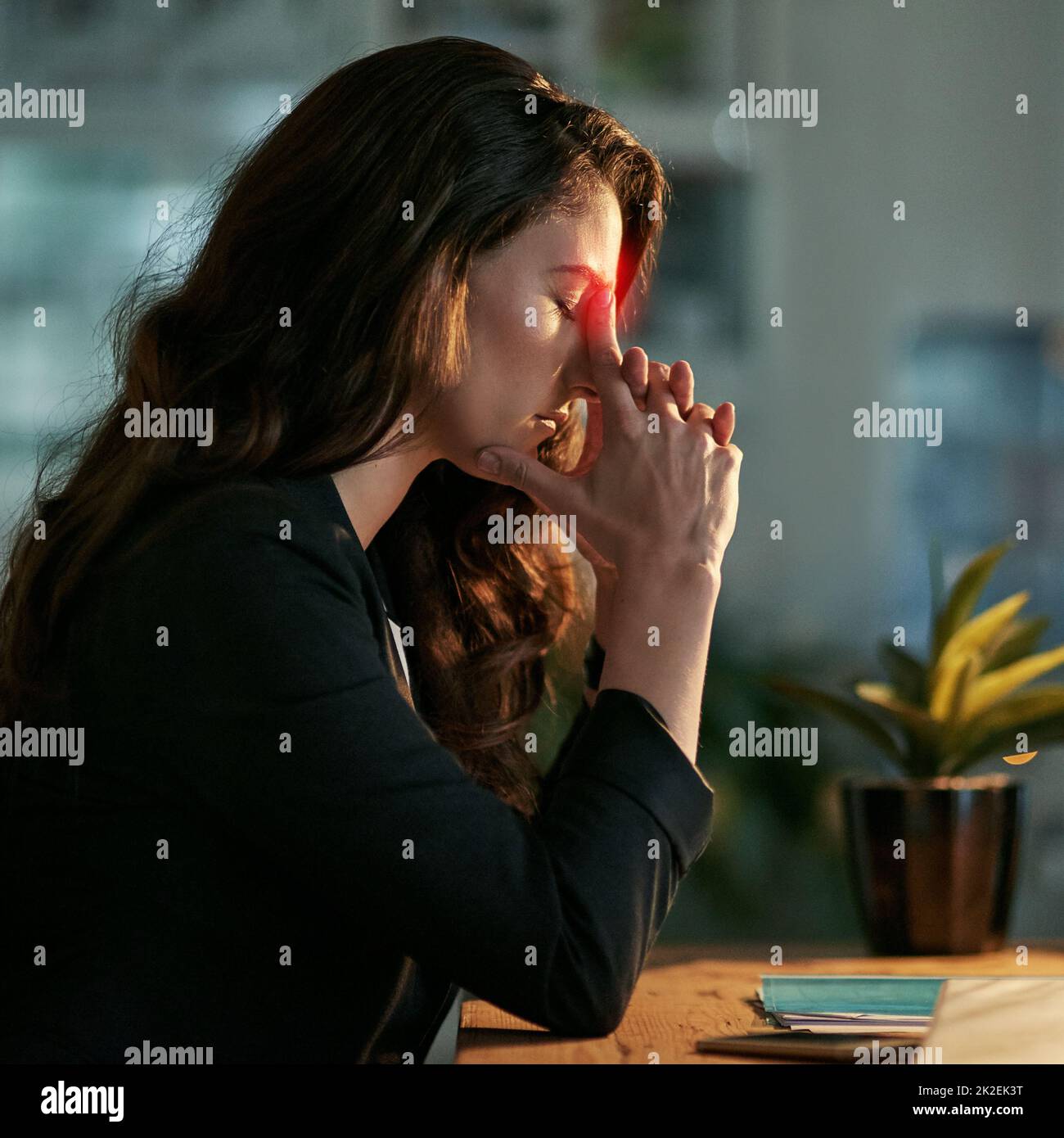This headache is pushing me back from work. Cropped shot of a stressed out businesswoman working late in an office. Stock Photo