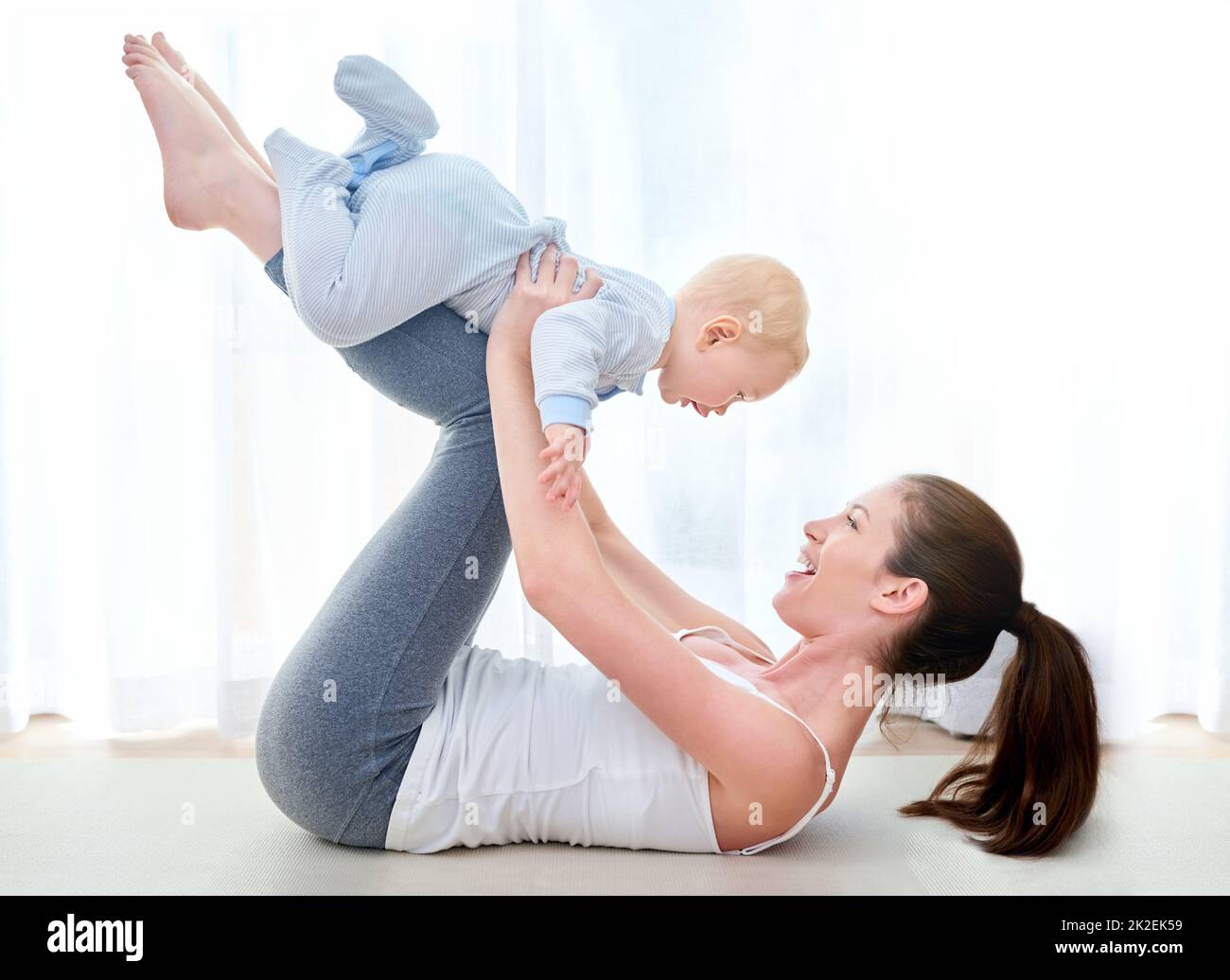 Mommy and me exercises. Shot of a young woman working out while spending time with her baby boy. Stock Photo