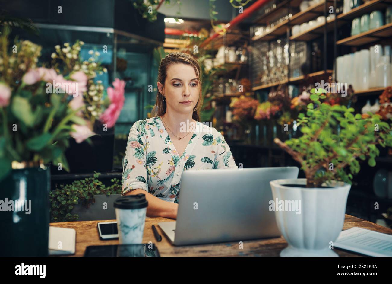 I have one more email to respond to. Cropped shot of an attractive young businesswoman sitting alone in her floristry and using her laptop. Stock Photo