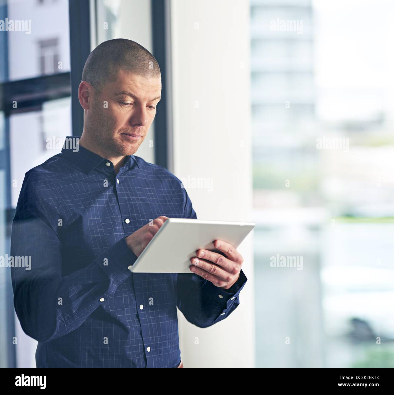 Smarter business research supported by smart technology. Shot of a businessman using a digital tablet in a modern office. Stock Photo