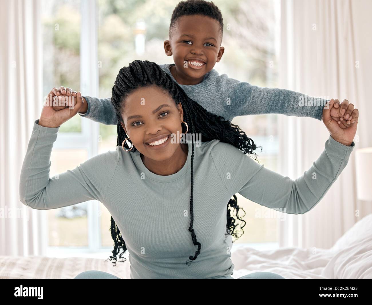 Mommys favourite boy. Cropped portrait of an attractive young woman sitting on the bed at home with her son on her back. Stock Photo