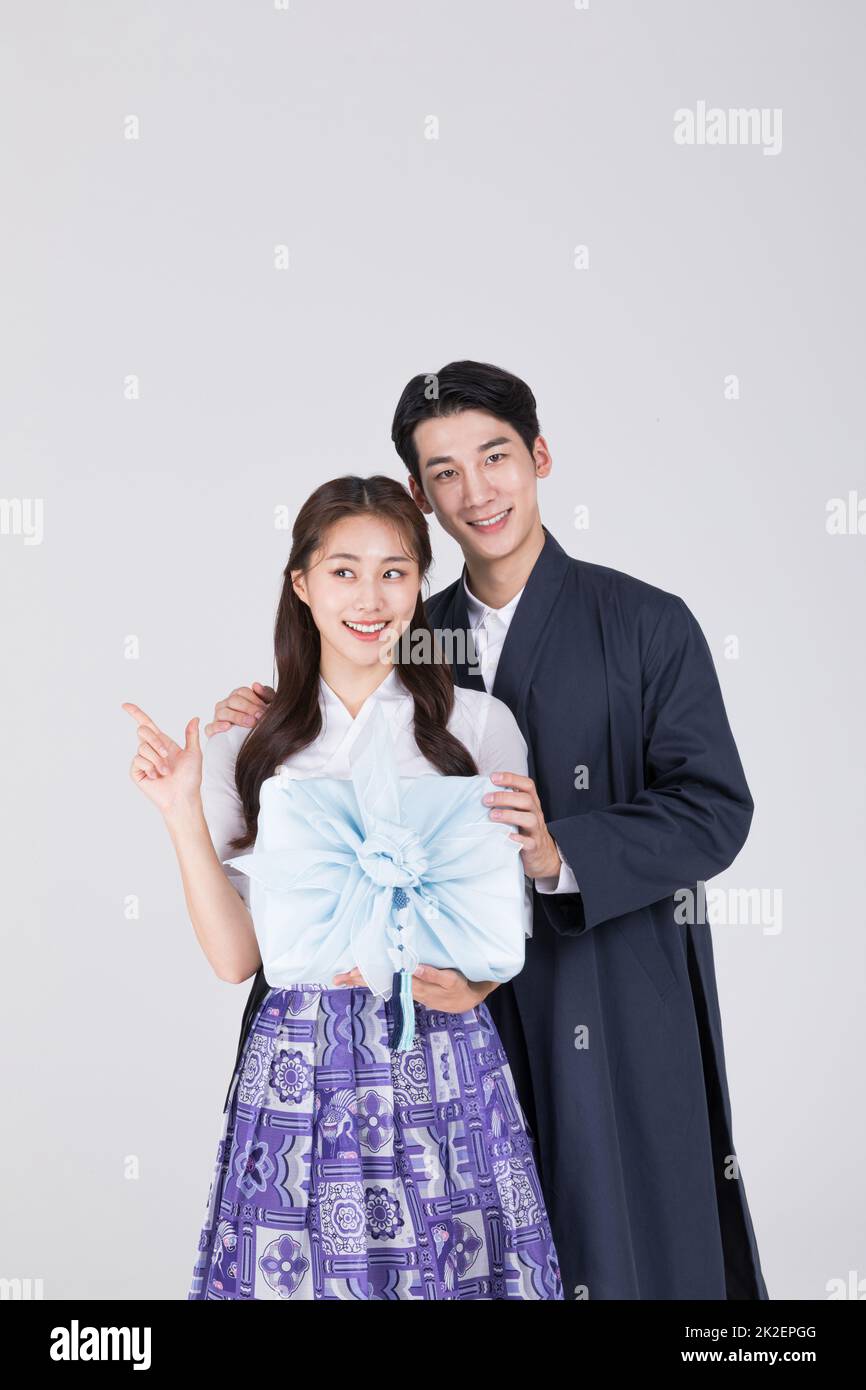 A Korean couple is standing wearing Korean traditional clothes
