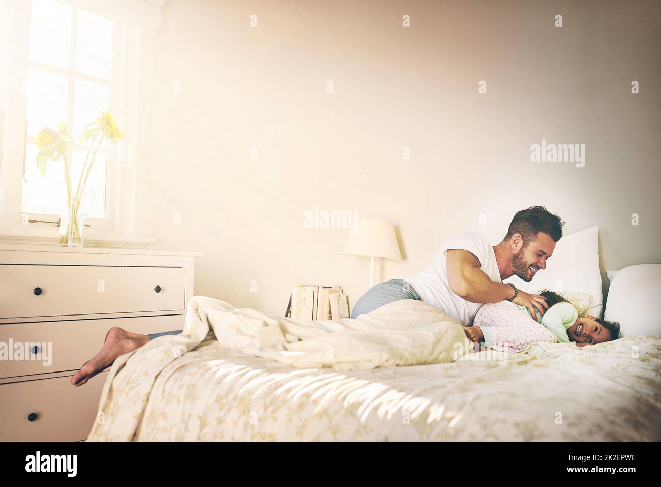 Getting tickle attacked. Shot of a cheerful father and daughter having a tickle fight on the bed at home. Stock Photo