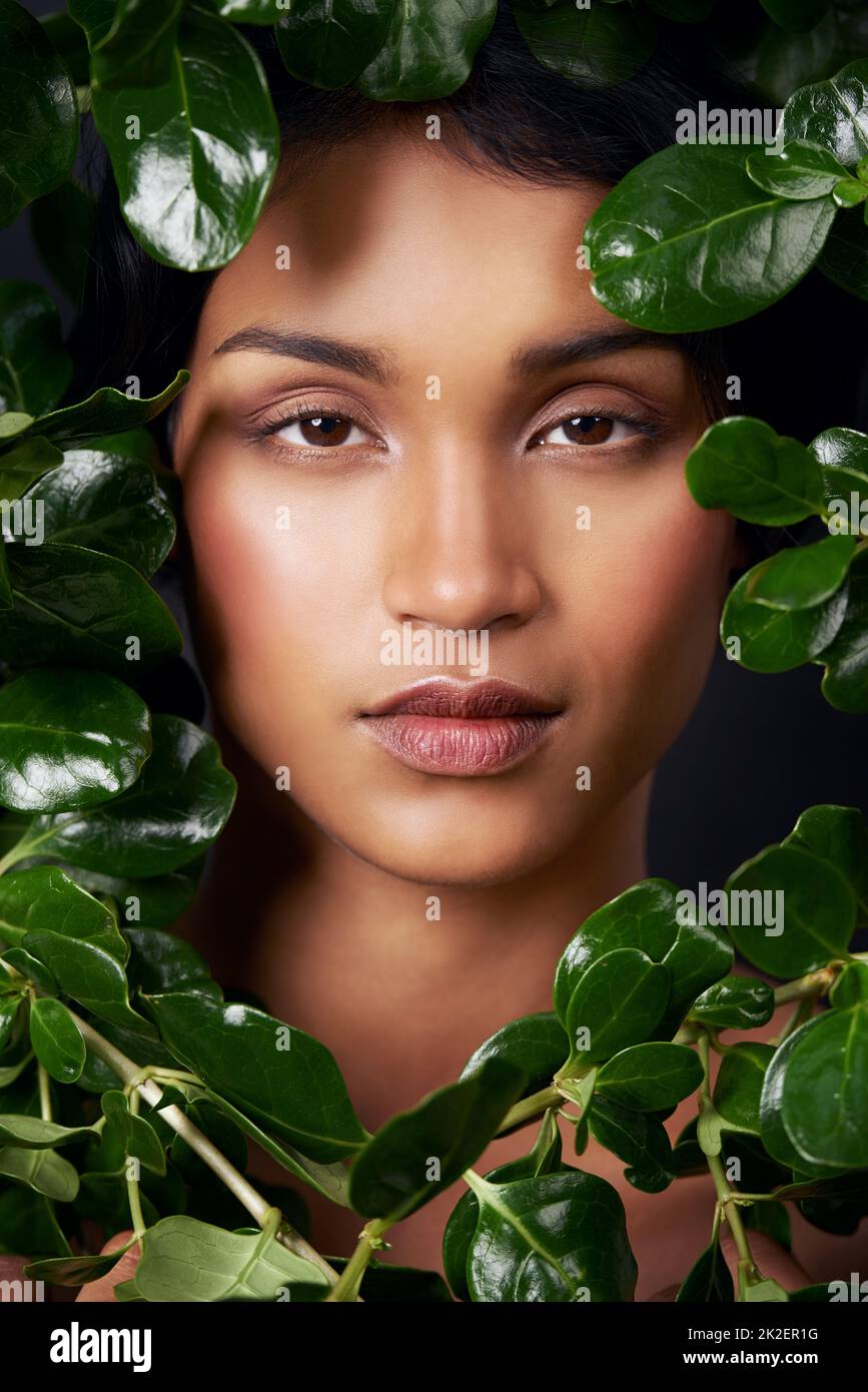 Wrapped in natures beauty. Studio shot of an attractive young ethnic woman surrounded by leaves. Stock Photo