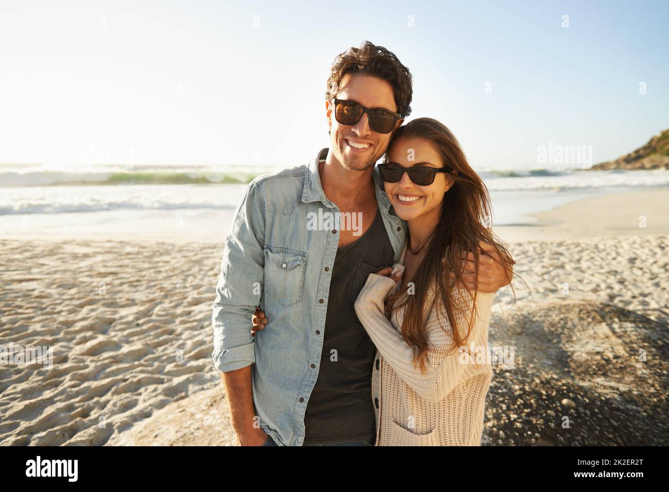 Enjoying the sea breeze and sun. Shot of a beautiful young couple standing side by side on the beach. Stock Photo