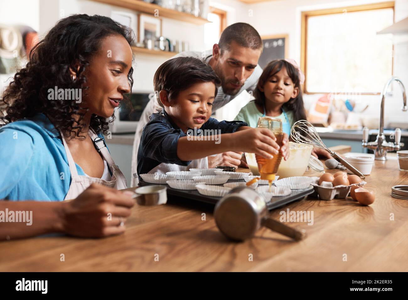 I want some extra honey in mine. Cropped shot of a young couple baking at home with their two children. Stock Photo