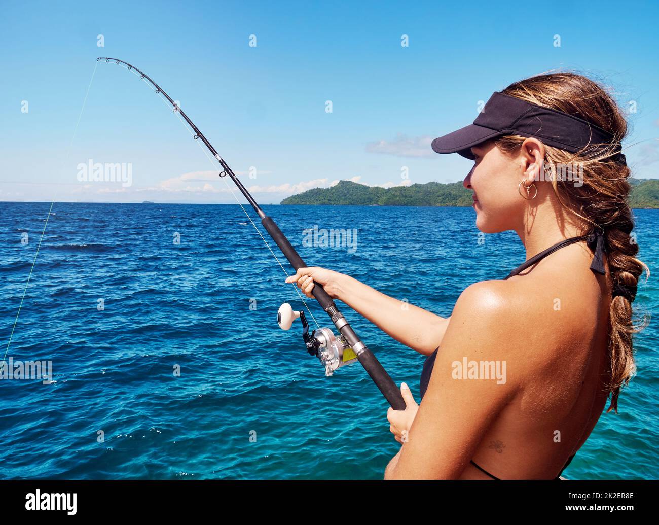Im just reeling in the good times. Cropped shot of an attractive young woman fishing out at sea. Stock Photo