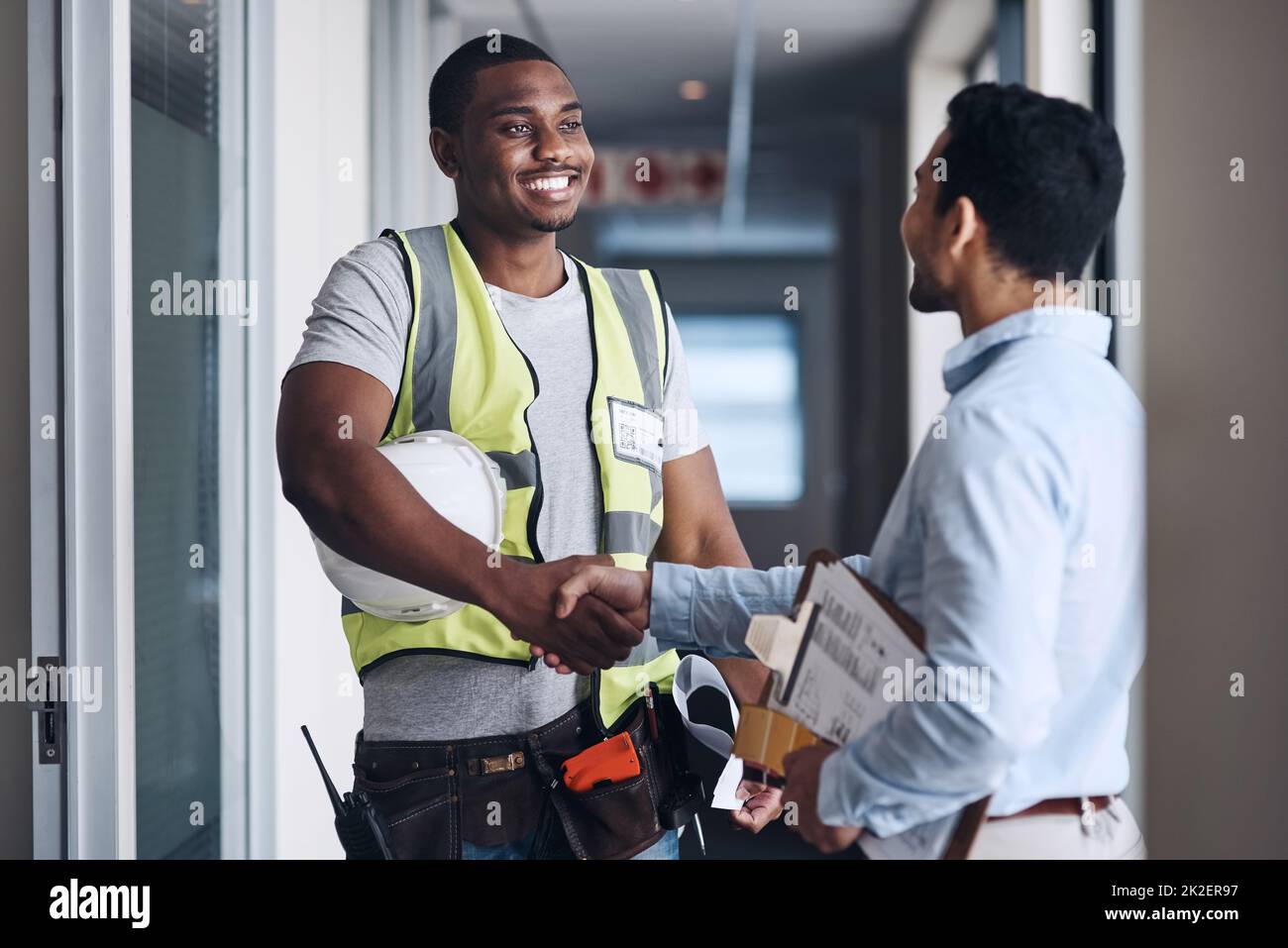 Well see you on Monday. Shot of two young architects standing together and shaking hands after a discussion about the room before they renovate. Stock Photo