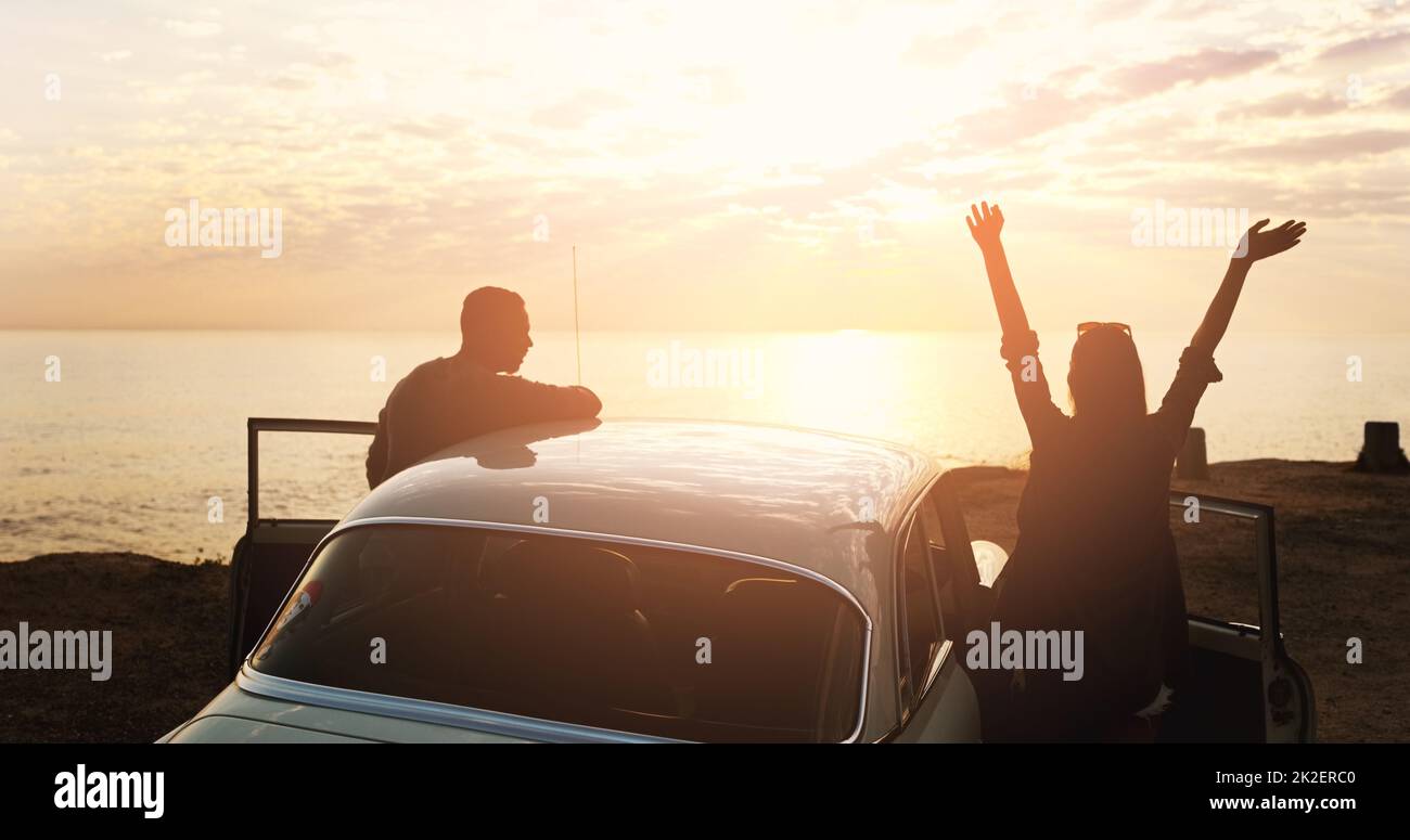 Winning is what lovers do. Cropped shot of a young couple cheering at the beach while out on a road trip. Stock Photo