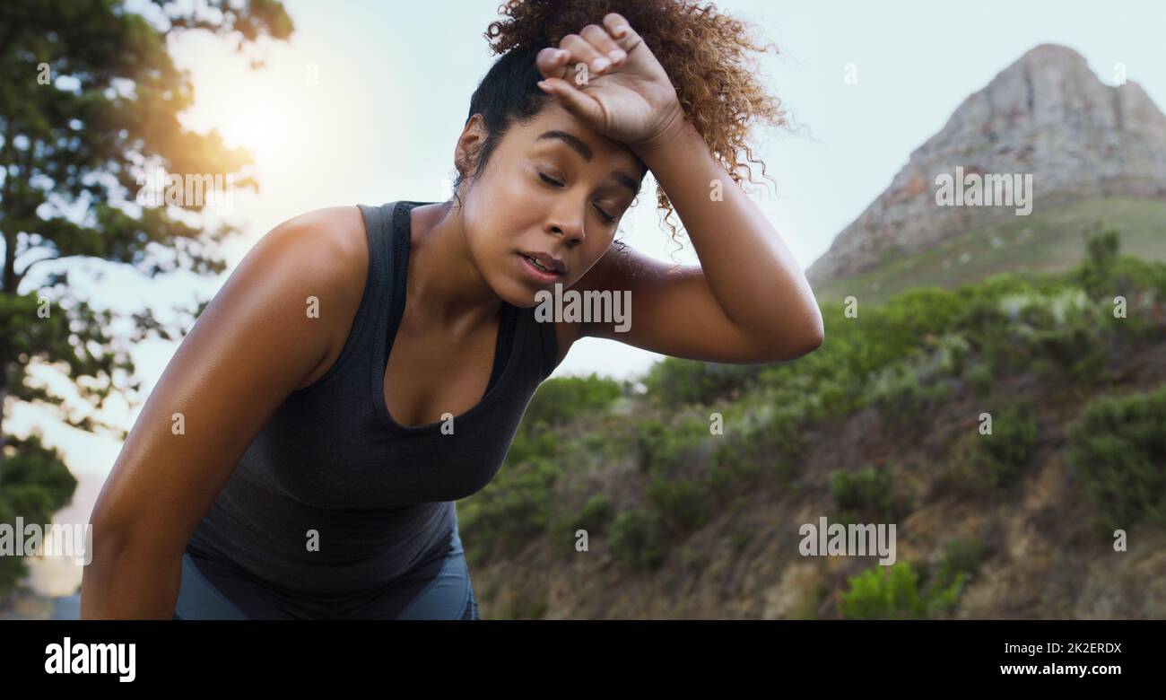 The path to a healthier lifestyle doesnt come without challenges. Shot of a sporty young woman taking a break while exercising outdoors. Stock Photo