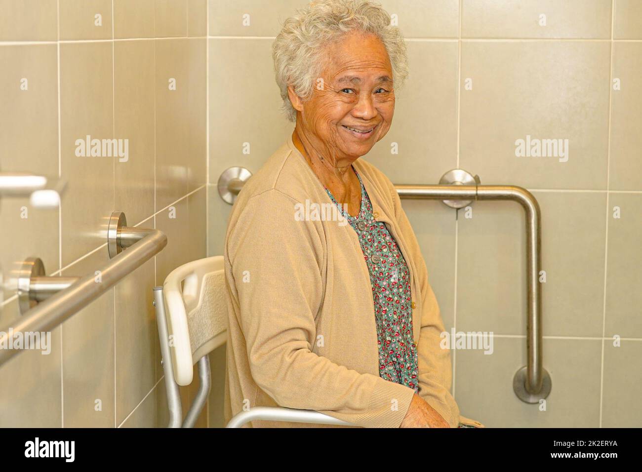 Asian elderly old woman patient use toilet support rail in bathroom