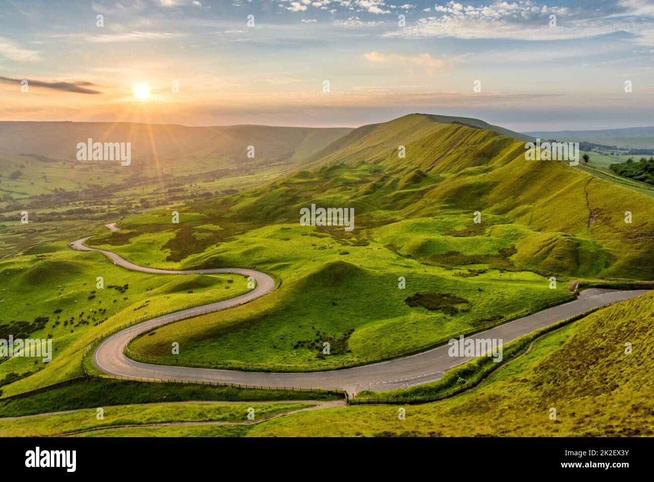Long winding country road leading through rural countryside in the English Peak District with beautiful evening sunlight. Stock Photo