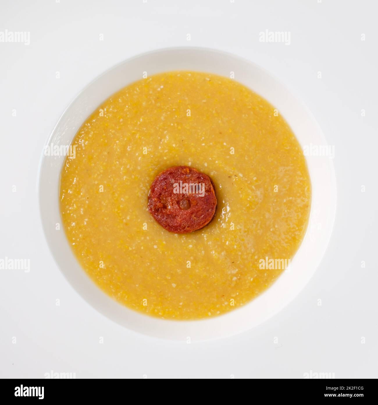 Polenta with butter and parmesan cheese and chorizo sausage in a plate Stock Photo