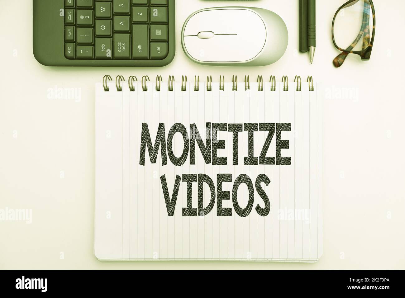 Conceptual caption Monetize Videos. Business showcase process of earning money from your uploaded YouTube videos Office Supplies Over Desk With Keyboard And Glasses And Coffee Cup For Working Stock Photo