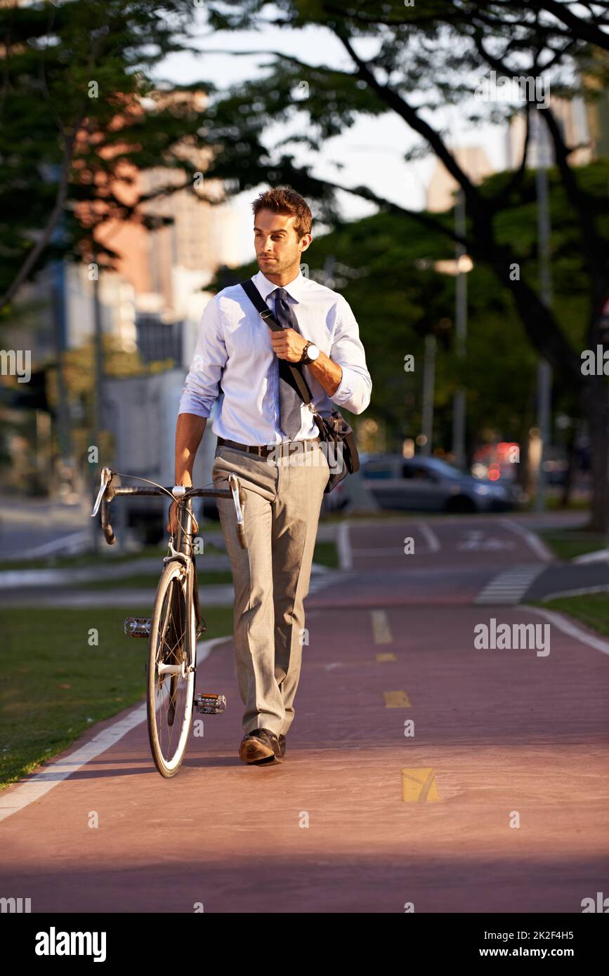 Keeping his carbon footprint as low as possible. Shot of a businessman commuting to work with his bicycle. Stock Photo