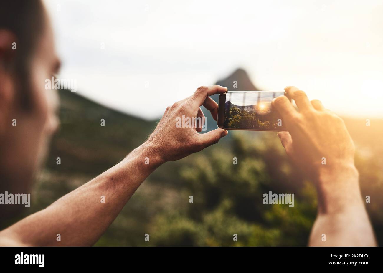 Taking the view home with him. Cropped shot of a man taking a picture of the scenery at the top of a mountain. Stock Photo