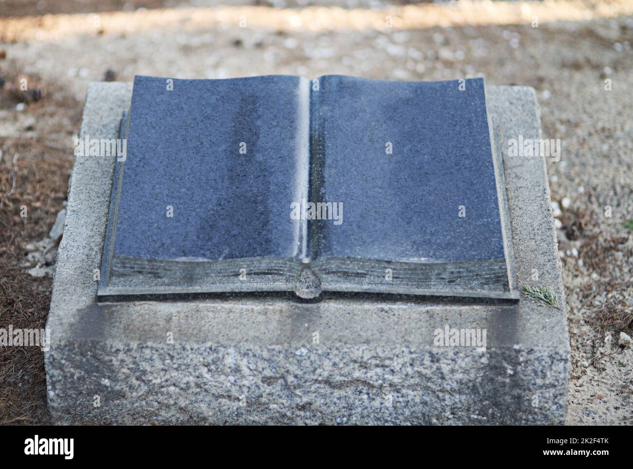 The holy book will forever be with them. Shot of a gravestone in a cemetery. Stock Photo