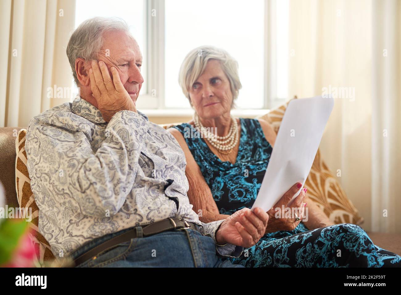 Less income, challenging outcomes. Shot of a senior couple going through their paperwork together at home and looking worried. Stock Photo