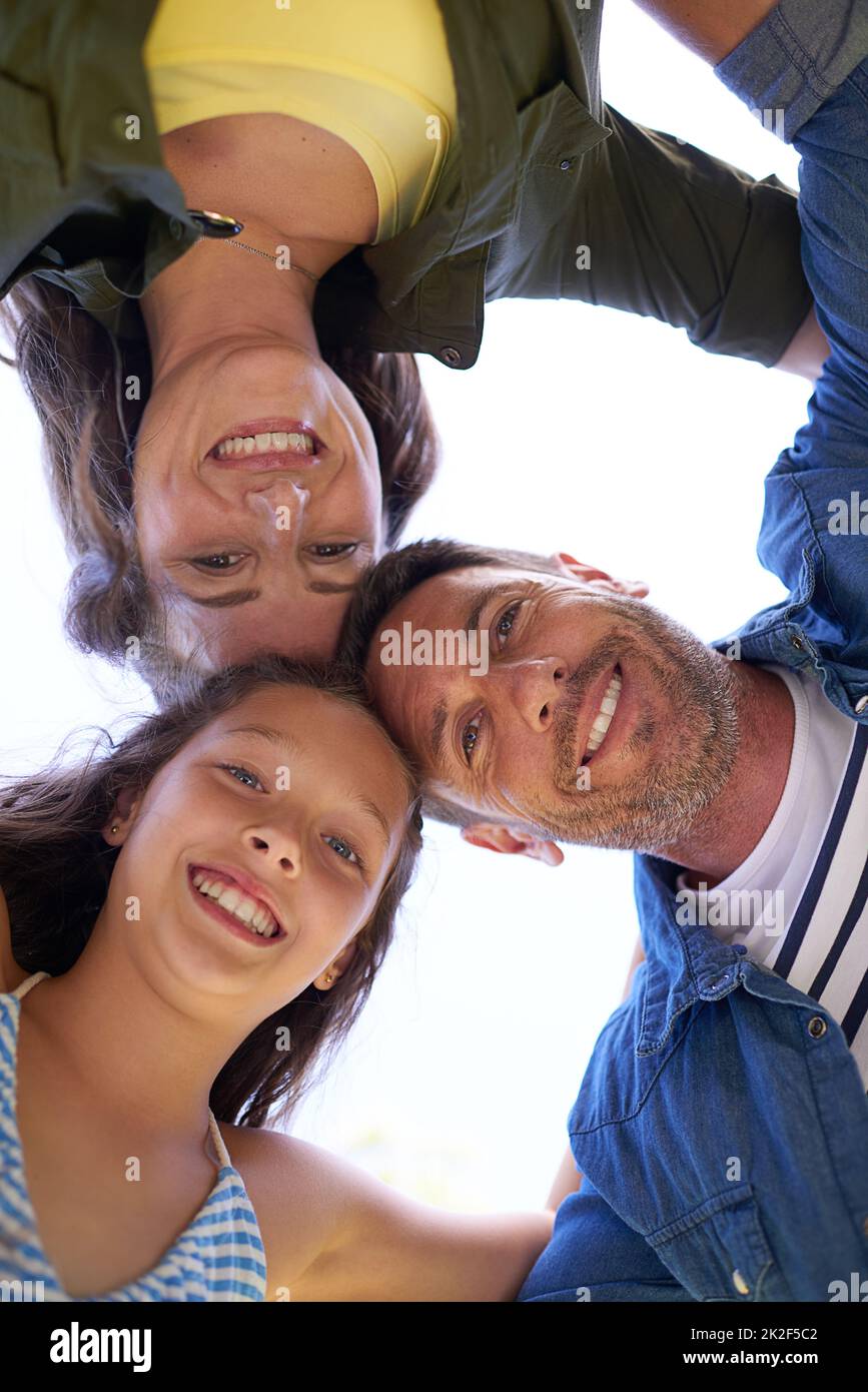 Family huddle. Low angle shot of a young family standing in a huddle outside. Stock Photo