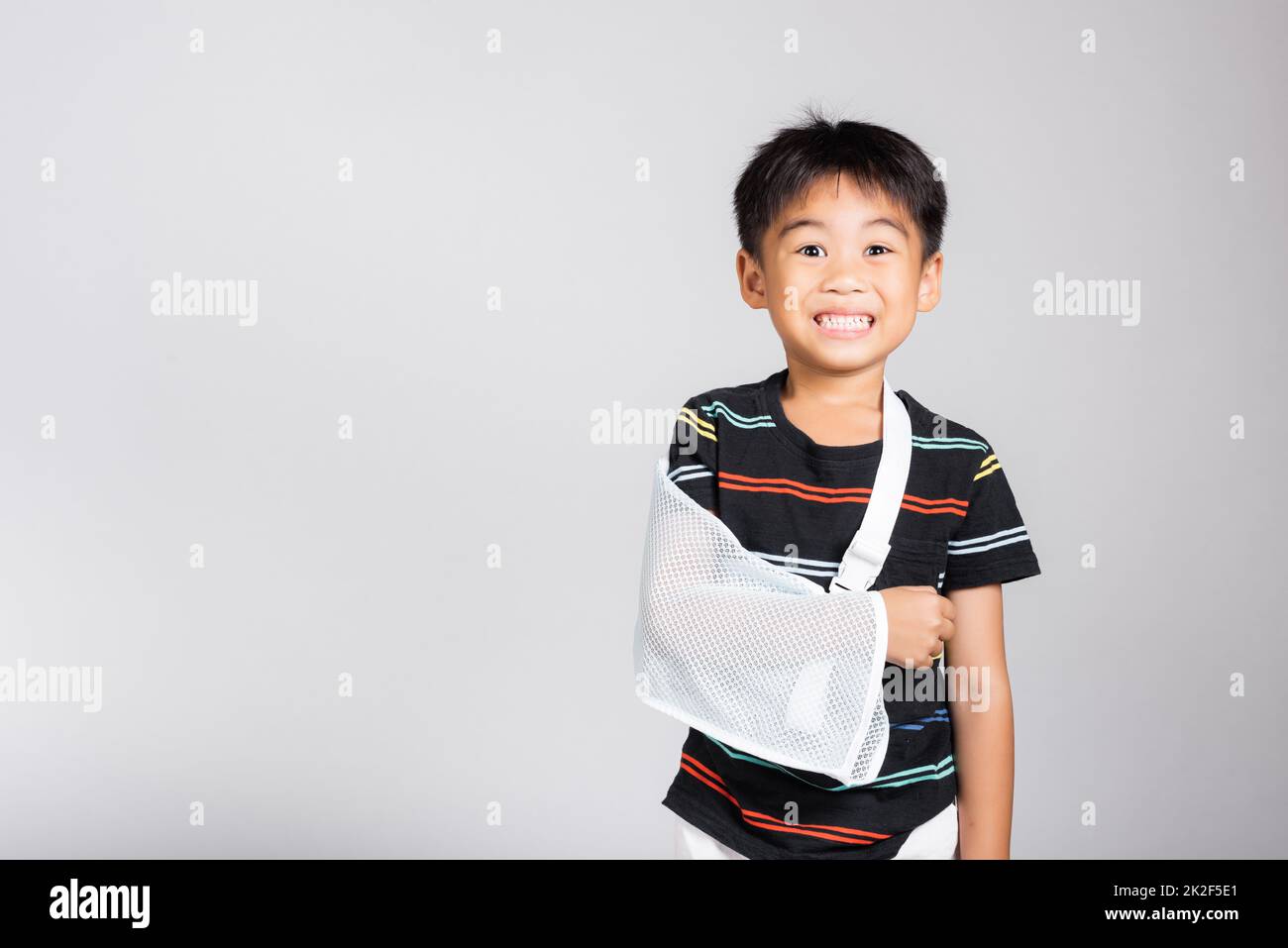 Little cute kid boy 5-6 years old hand bone broken from accident with arm splint in studio shot isolated Stock Photo