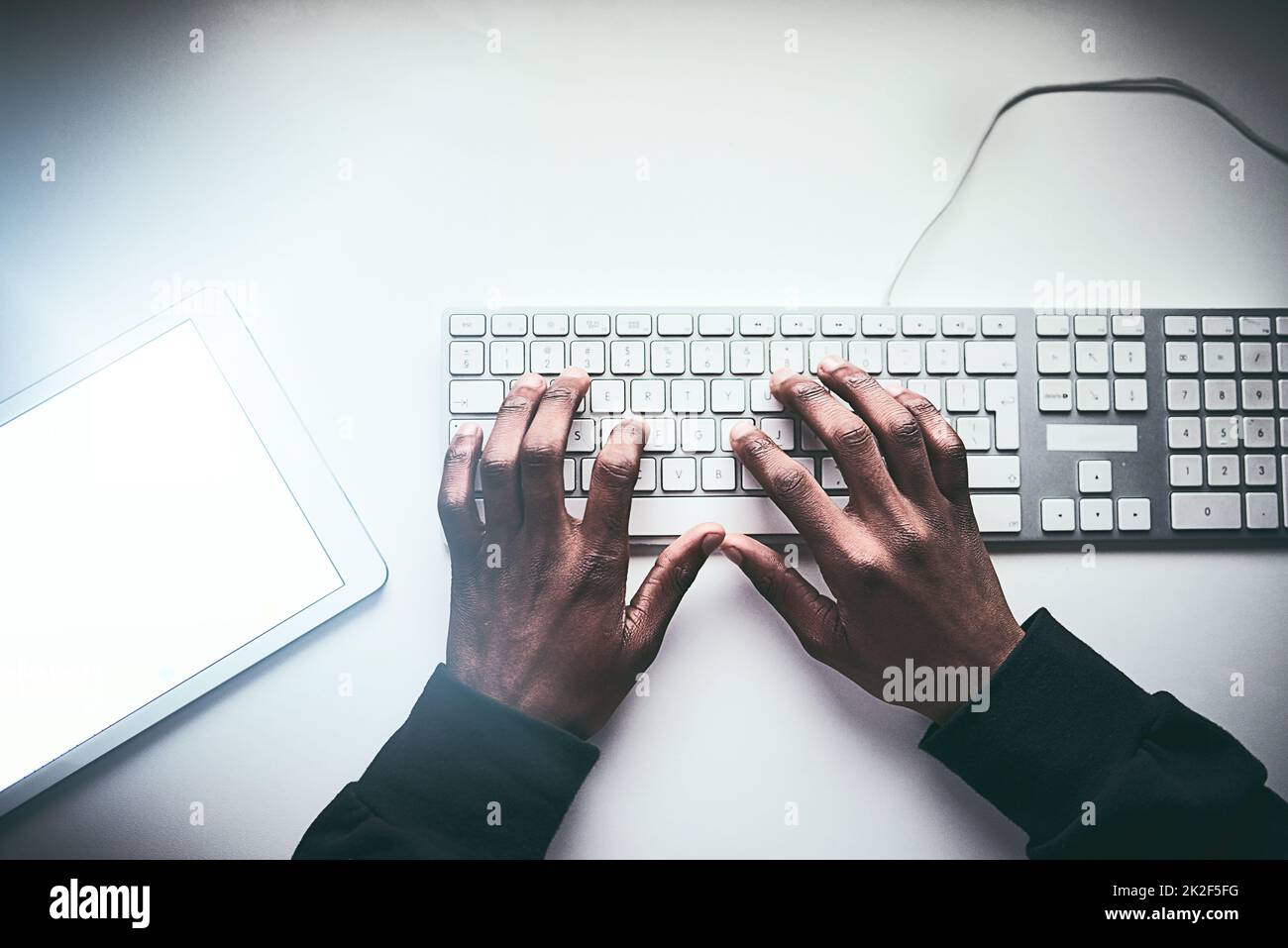 Fastest fingers on the web. High angle shot of an unrecognizable man typing on a keyboard while working late in the office. Stock Photo