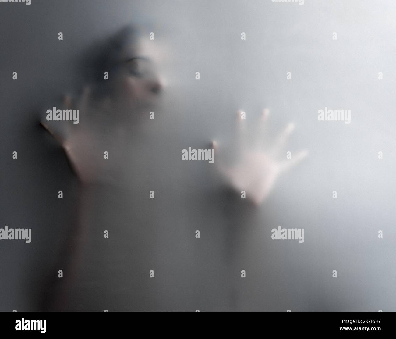 Keep trying but there is no escape. Cropped shot of an unrecognizable woman trapped behind a hazy film. Stock Photo