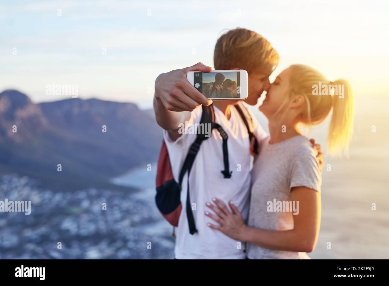 Capturing their kiss. Cropped shot of a young couple taking a selfie while on a hike. Stock Photo