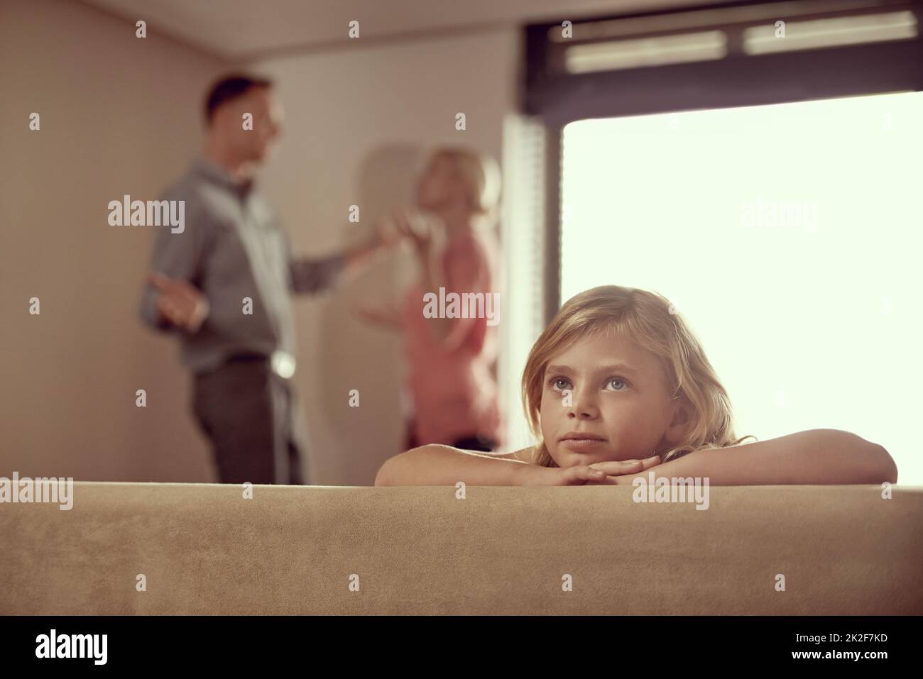 Why do they have to fight. Shot of a little girl looking unhappy as her parents argue in the background. Stock Photo