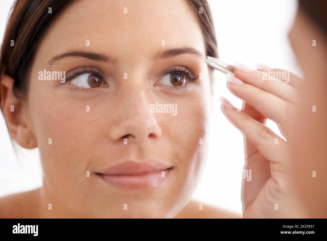 Shes already perfect. An attractive young woman plucking her eyebrows. Stock Photo